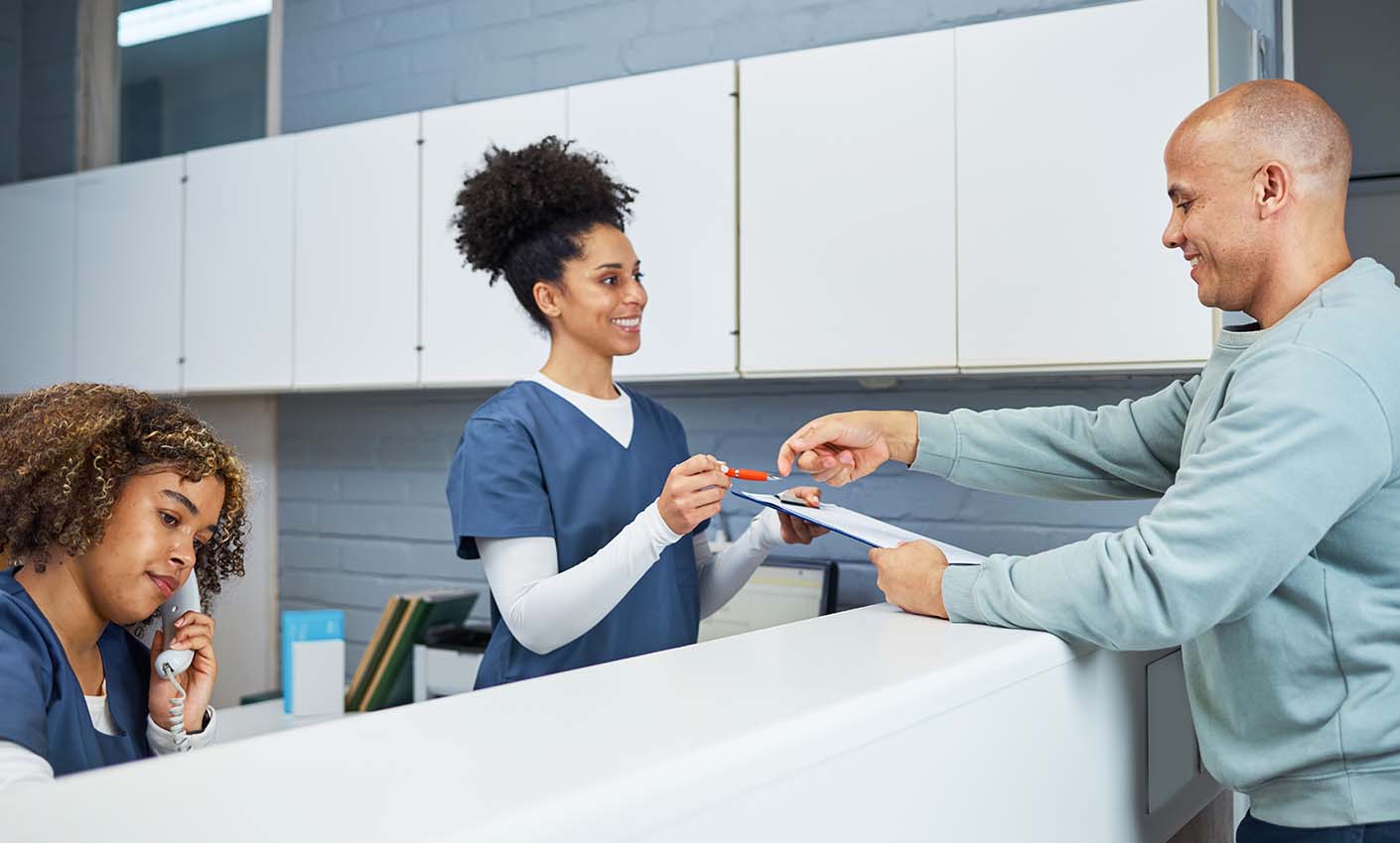 Reception desk interaction with staff member handing an item to a visitor.