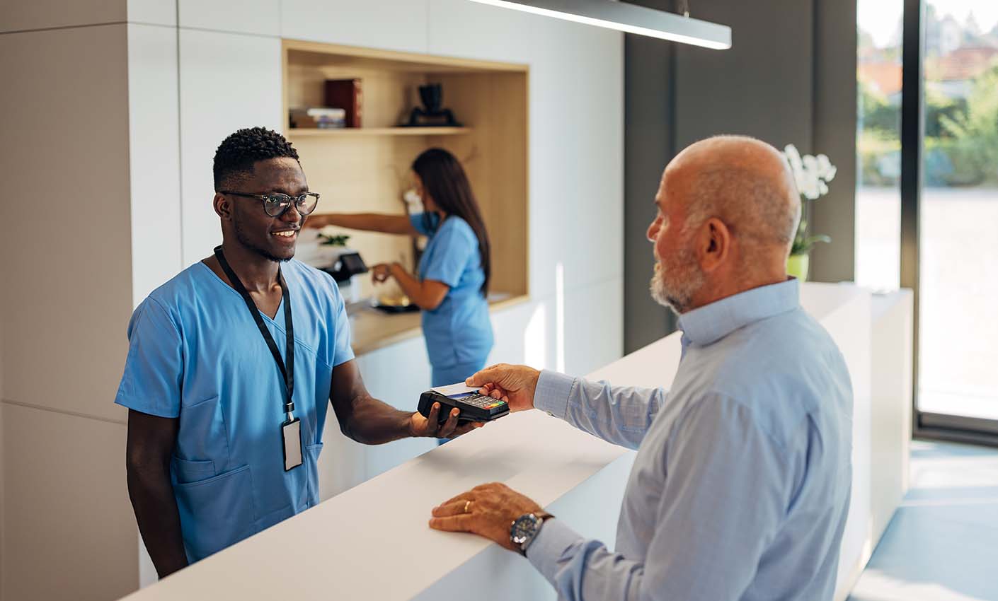Healthcare worker with a visitor who is paying at reception.
