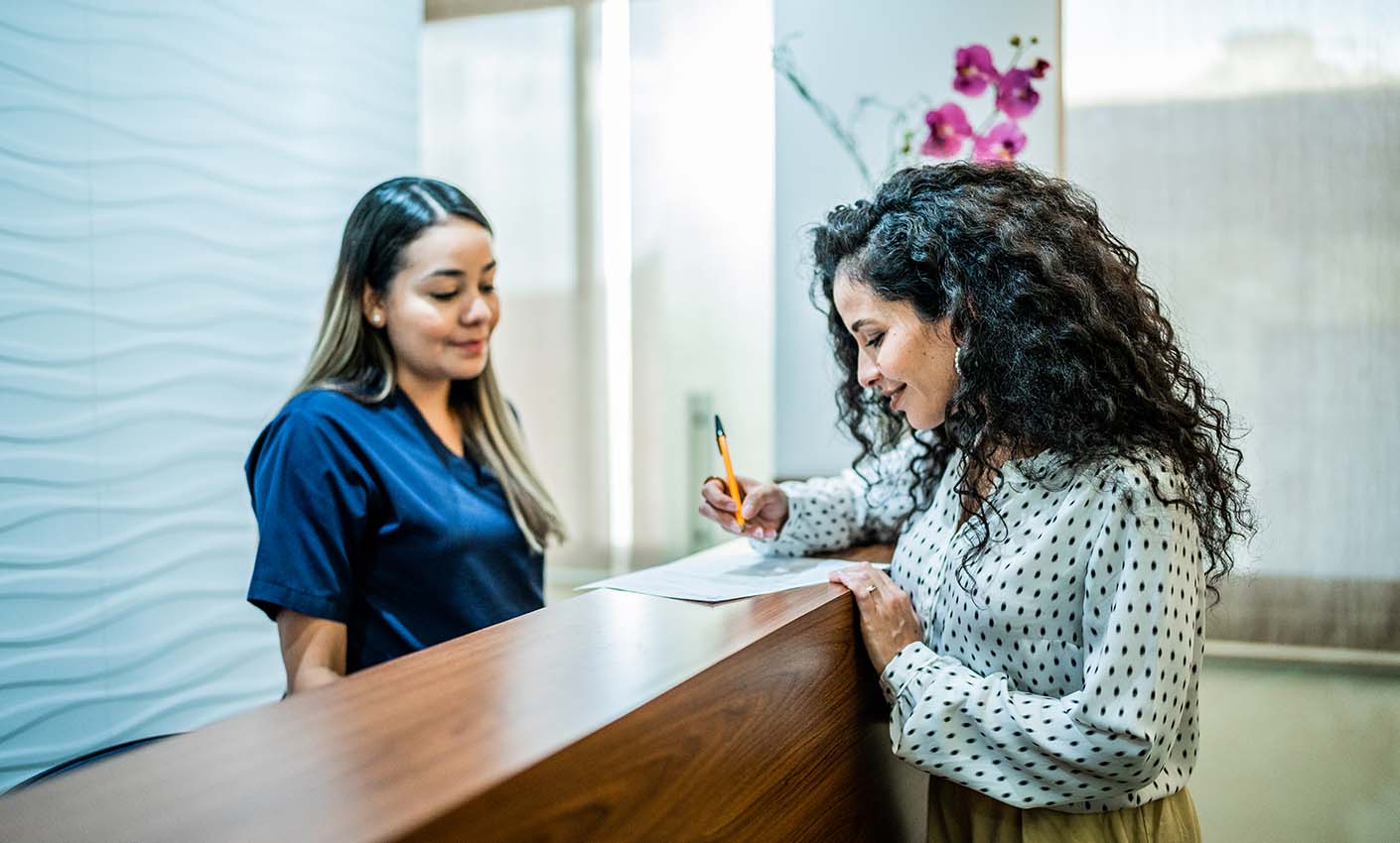 Reception desk interaction between a staff member and a visitor.